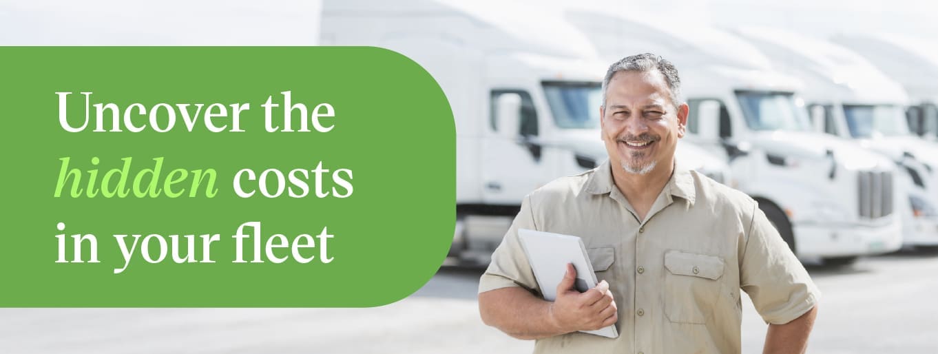 Fleet manager reviewing cost-per-mile data on a tablet near semi trucks