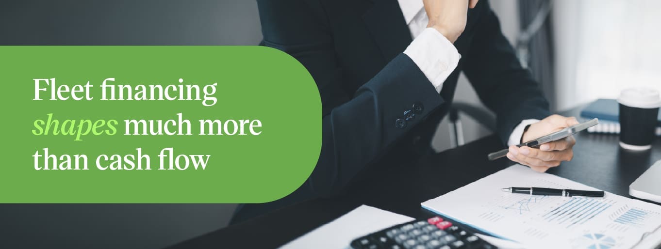 Businessman signing fleet financing paperwork with a calculator on the desk